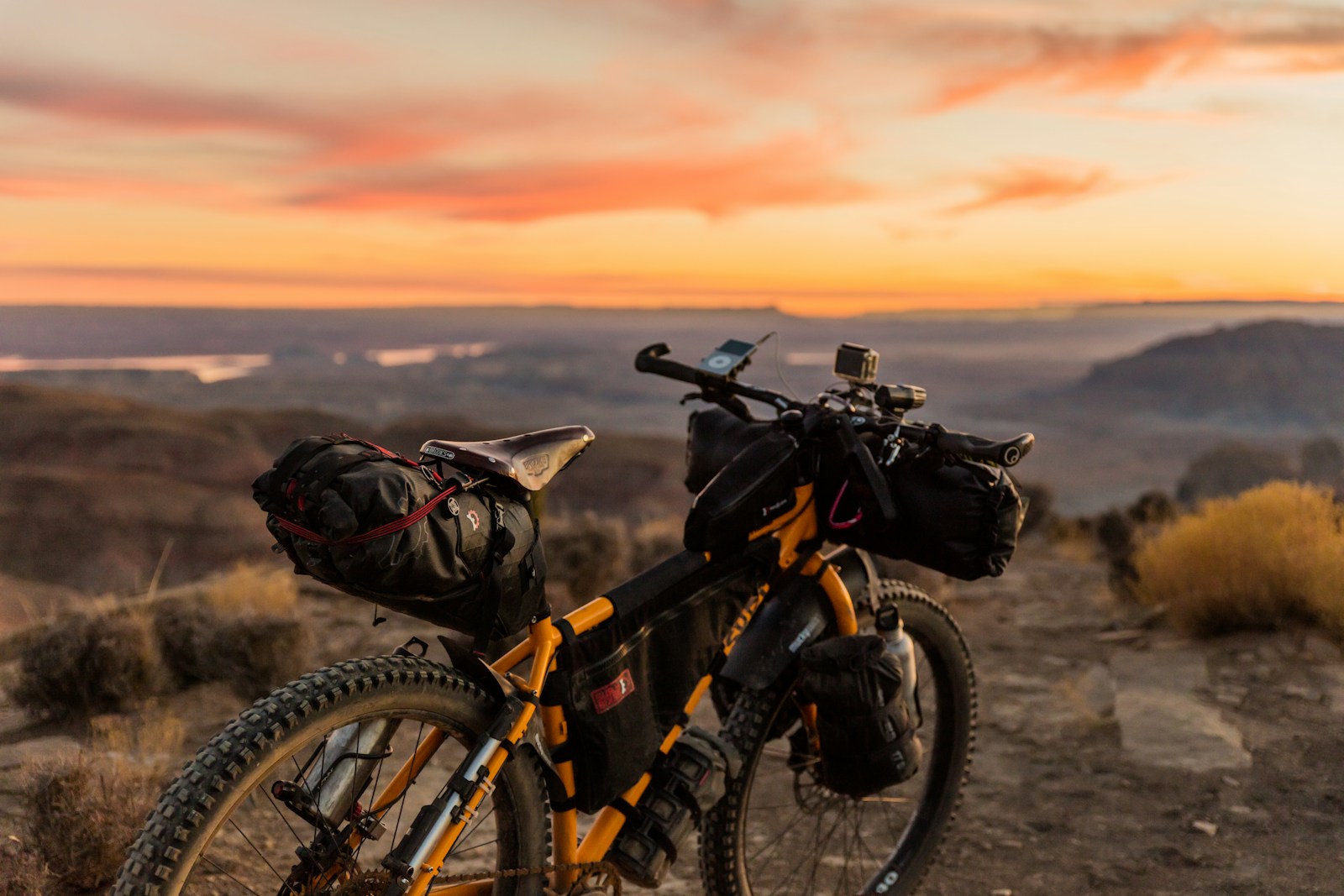 Orange and black mountain bike parked on a hillside trail.