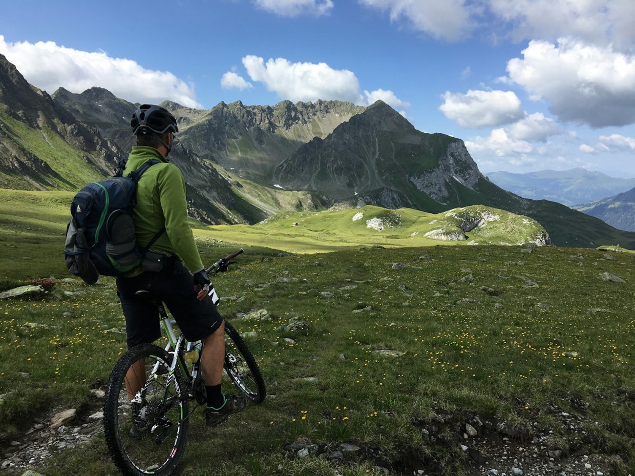 Rider standing with mountain bike on a high ridge.