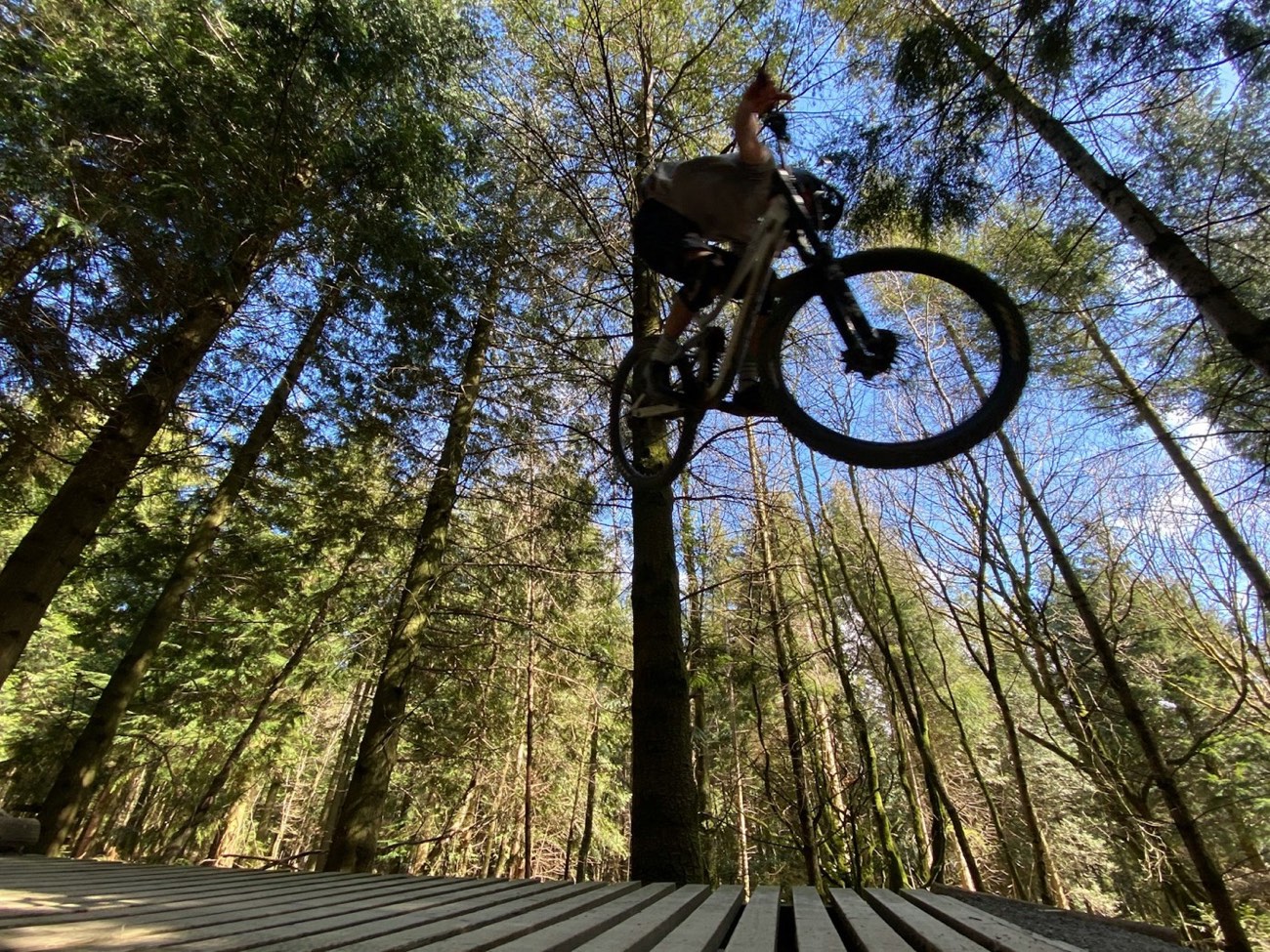 Mountain biker launching off a wooden jump.